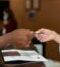 Close-up of a hotel receptionist receiving a credit card from a guest, highlighting a transaction at check-in.